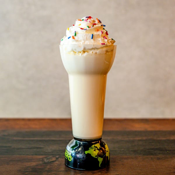 Vanilla milkshake with whipped cream and colorful sprinkles in an International Burgers glass.