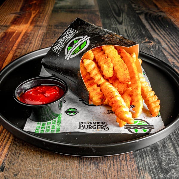 International Burgers' seasoned crinkle-cut fries in a branded container with a side of ketchup.