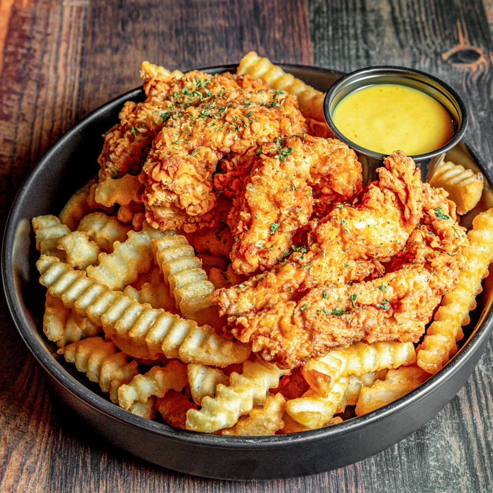 Crispy fried chicken tenders and crinkle-cut fries with a side of honey mustard dipping sauce.